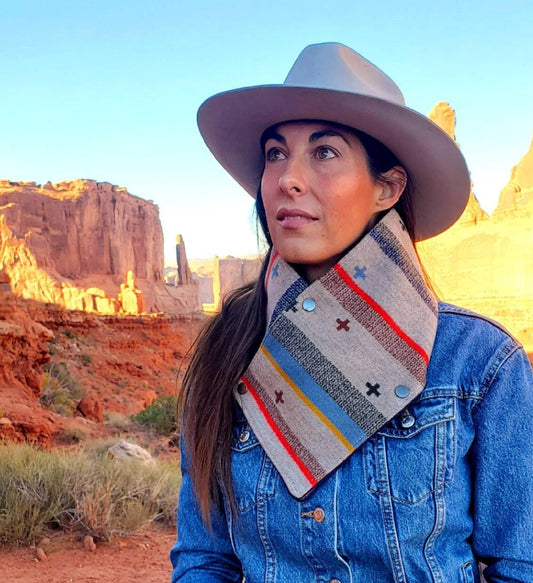 Western cowl neck scarf is worn by model overlooking red rocks & looks similar to bandana or neck gaiter. Made with Pendleton® blanket-weight wool, the design features green, brown, tan, blue, red geometric shapes that are popular in the Southwest.