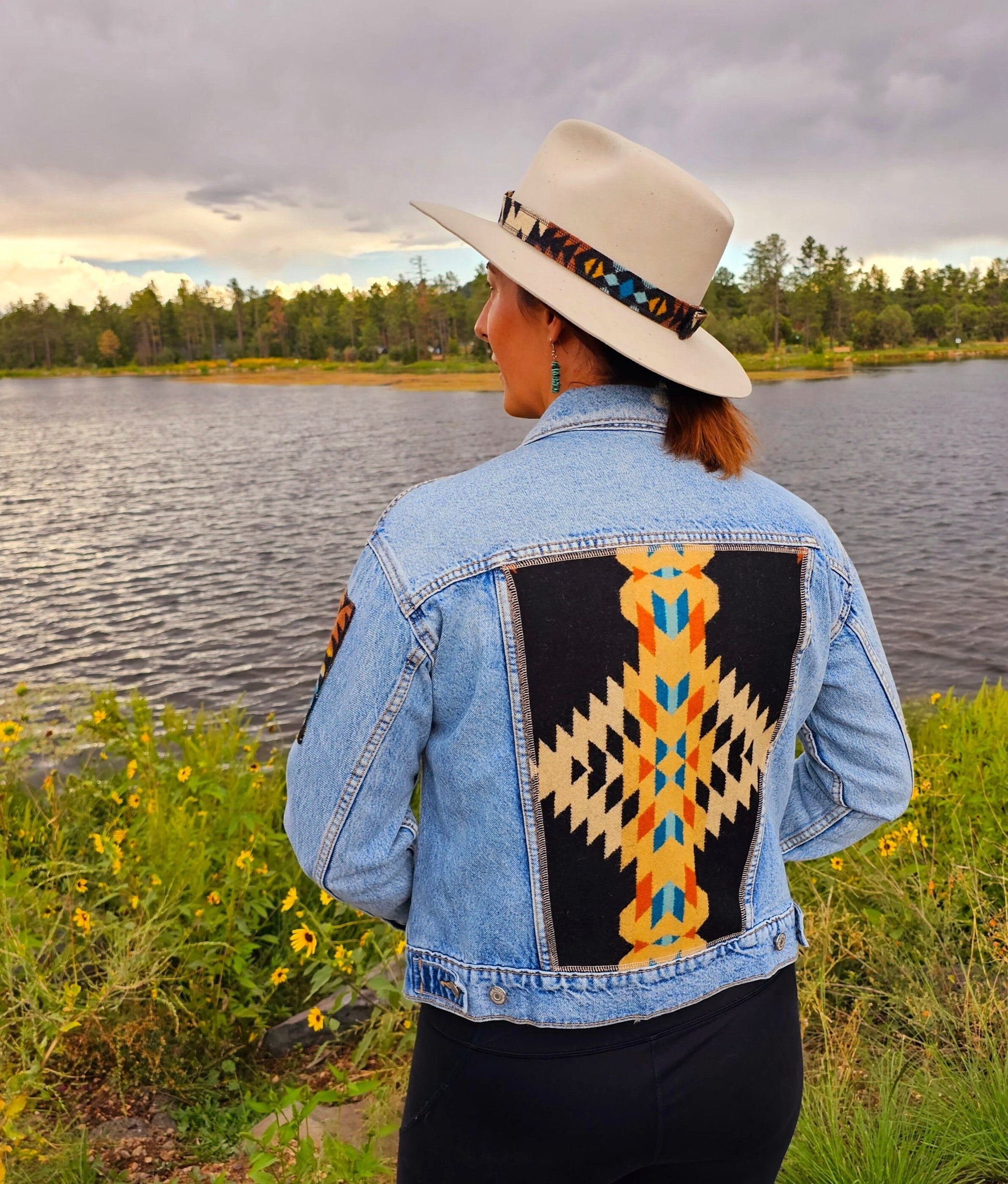 Model is standing in front of lake, wearing upcycled denim jacket with Pendleton® wool patches and back panel.