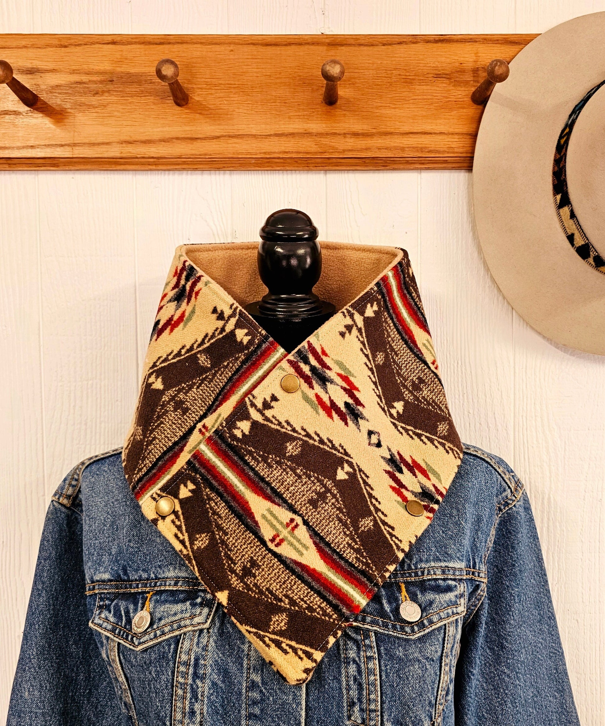 Western cowl neck scarf is displayed on mannequin & looks similar to bandana or neck gaiter. Made with Pendleton® blanket-weight wool, the design features brown, tan, red and moss green geometric shapes that are popular in the Southwest.